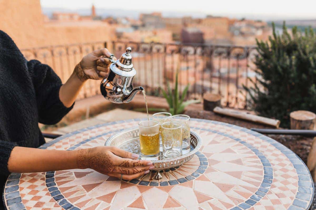 A person pouring traditional Moroccan tea into glasses.