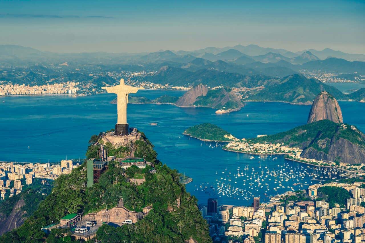 Panorama aéreo, filmado de helicóptero, da Baía de Botafogo com o Cristo Redentor e o Pão de Açúcar no Rio de Janeiro