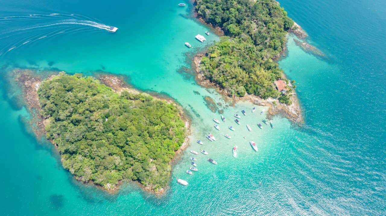 Vista aérea de duas ilhas rodeadas de água turquesa e vários barcos e lanchas