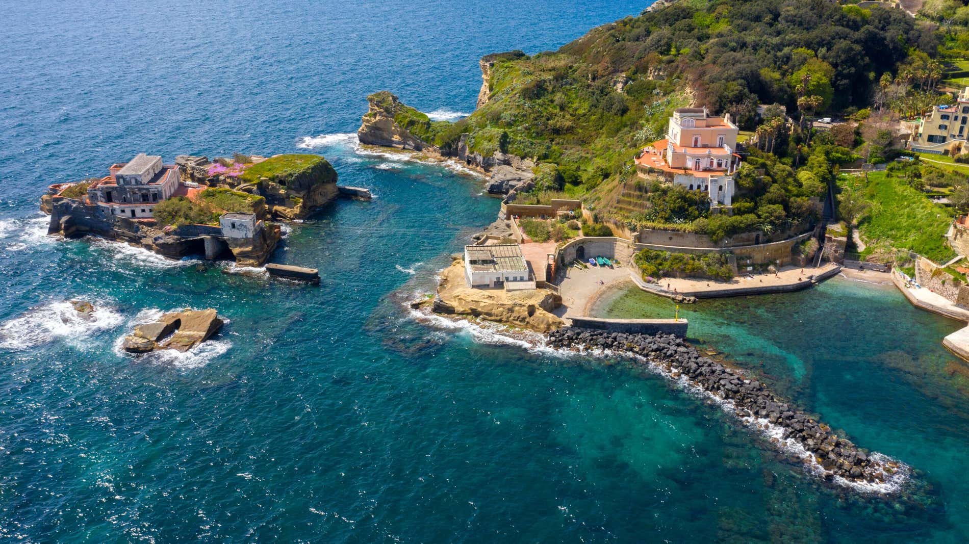 Panoramica di una piccola spiaggia con alcune case sulla costa rocciosa di Napoli