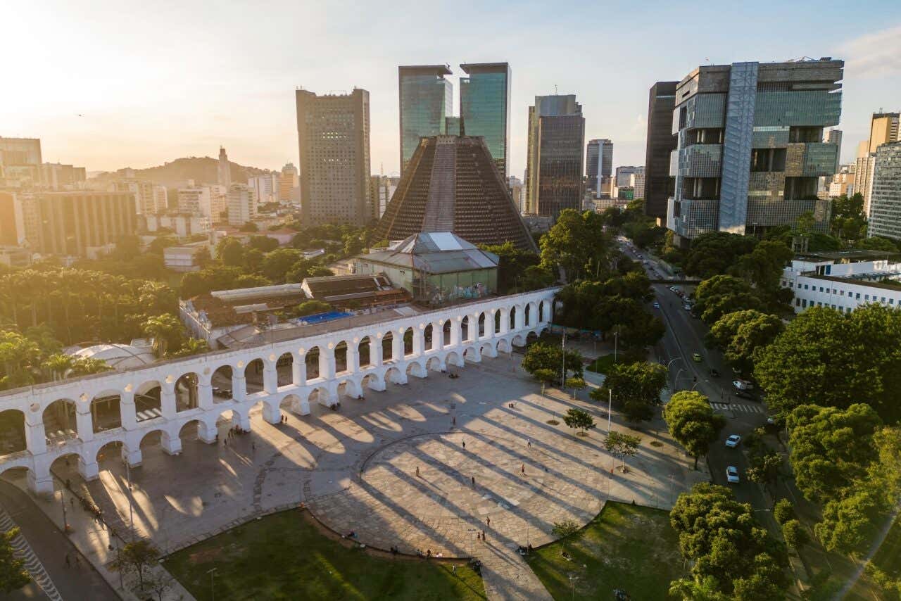 Vista aérea do aqueduto Arcos da Lapa com o centro da cidade do Rio de Janeiro ao pôr do sol com outros edifícios ao fundo
