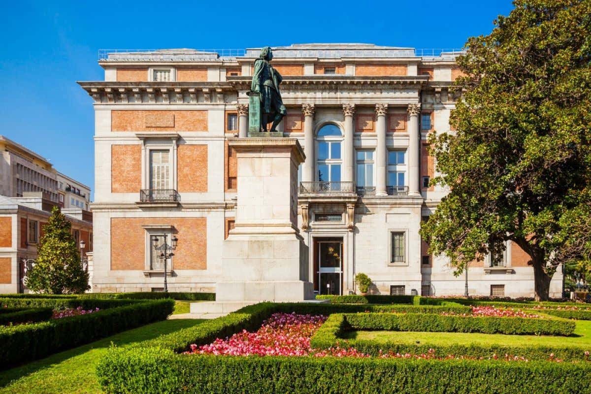 Views of the gardens and a statue in front of the Museo del Prado on a sunny day.