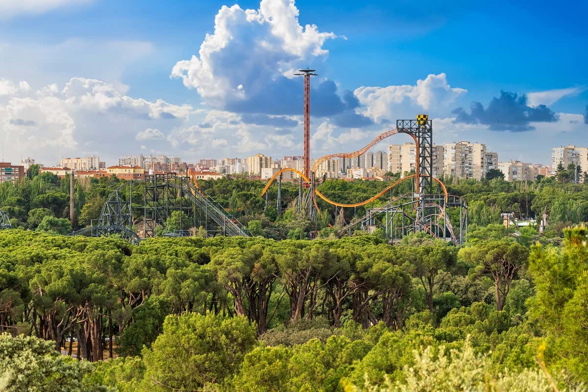 Montagne russe du parc d'attractions de Madrid au milieu des arbres et ville en arrière-plan