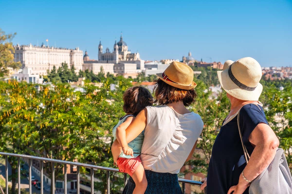 Deux personnes et un enfant de dos avec la vue sur le Palais royal et la cathédrale de Madrid en arrière-plan