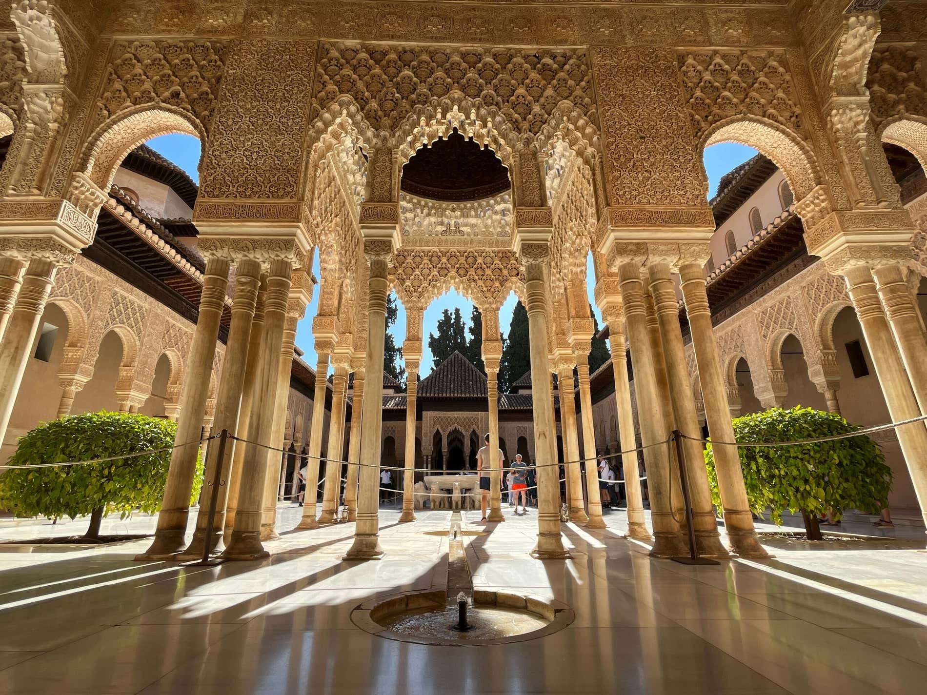 Patio de los Leones dell'Alhambra di Granada, con una fontana sotto arcate decorate e alcuni turisti sullo sfondo