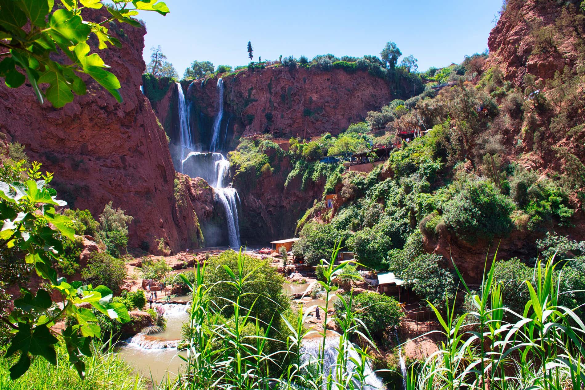 Cascate fra rocce rossastre e vegetazione a macchie