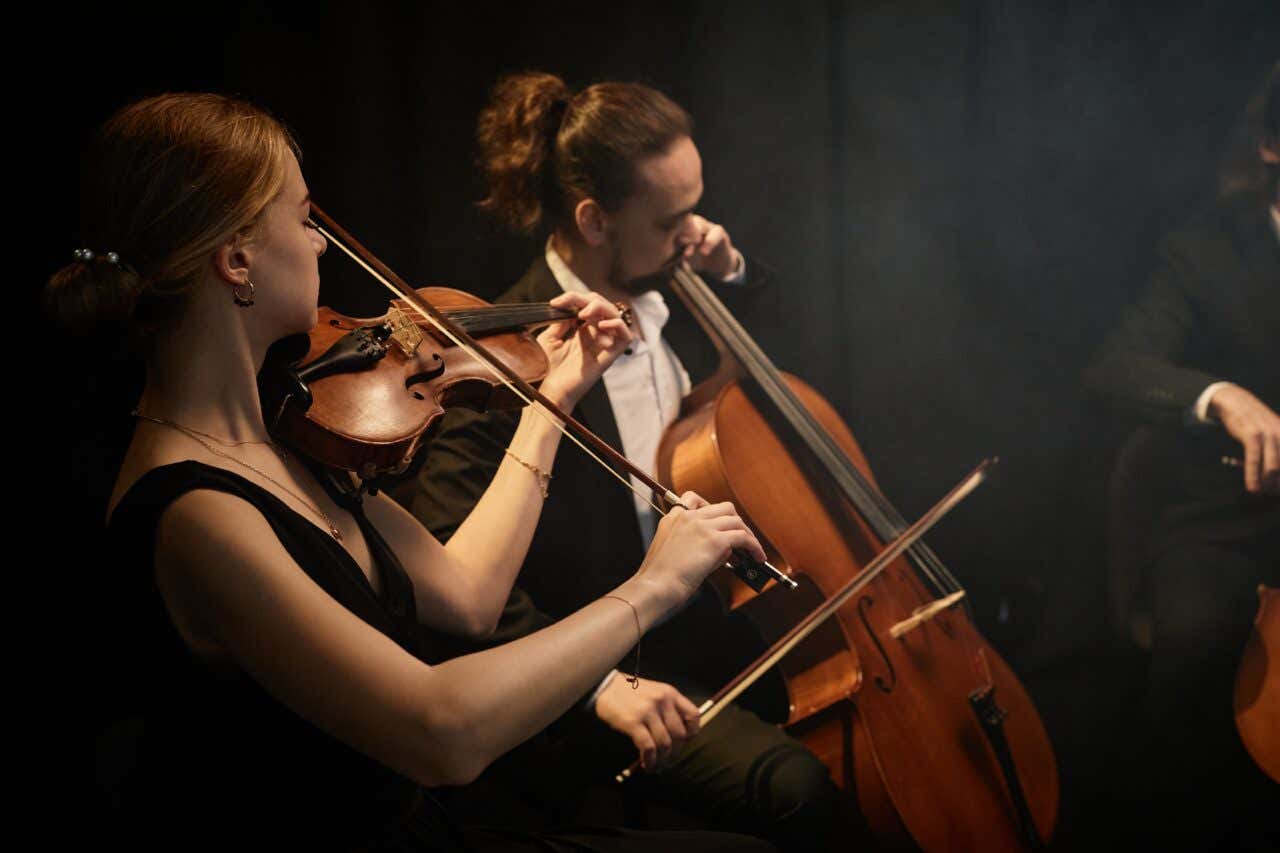 Una musicista di violino e un violoncellista durante un concerto con uno sfondo nero