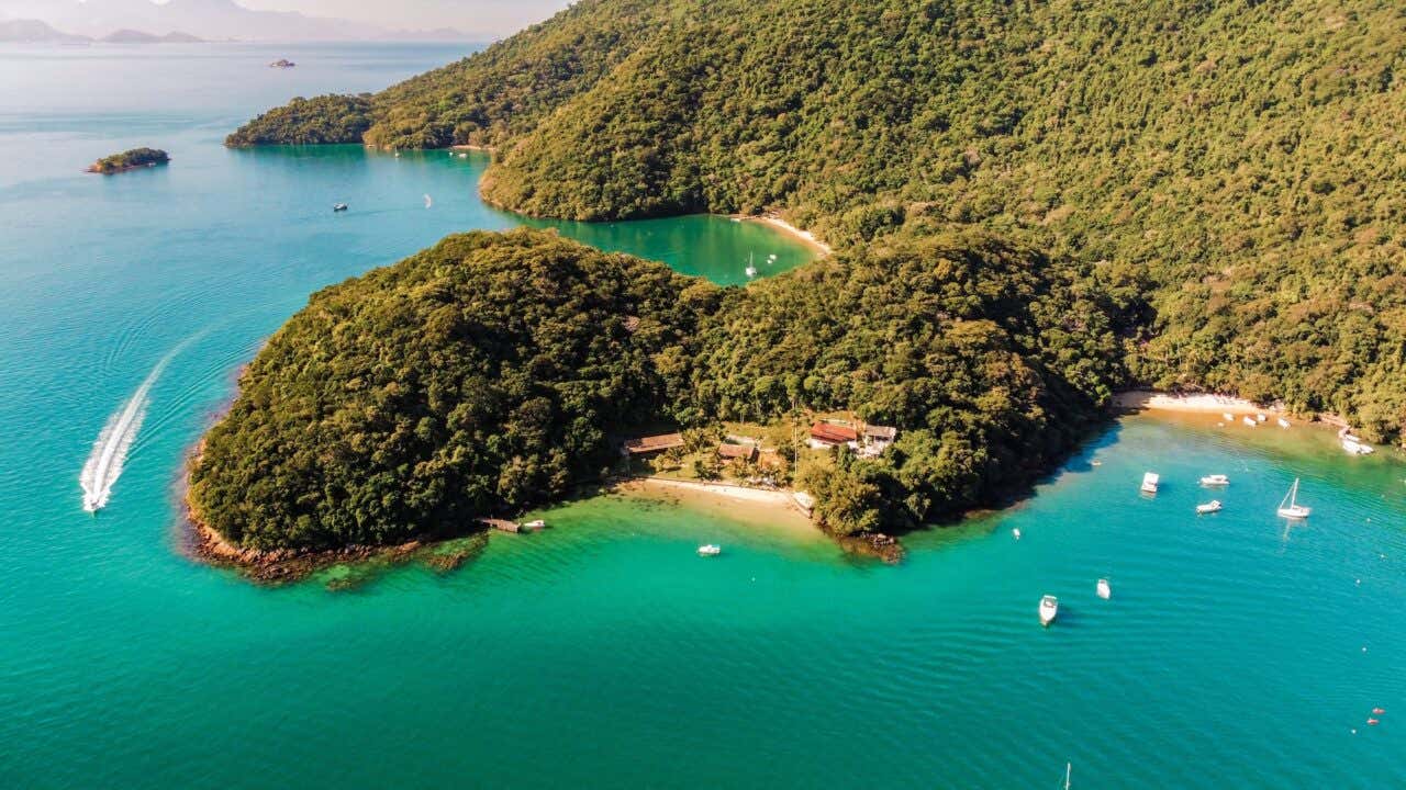 Vista aérea do oceano verde-esmeralda e da costa com frondosa vegetação