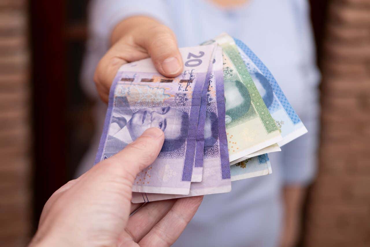 Una mano dà dei dirham a un'altra mano