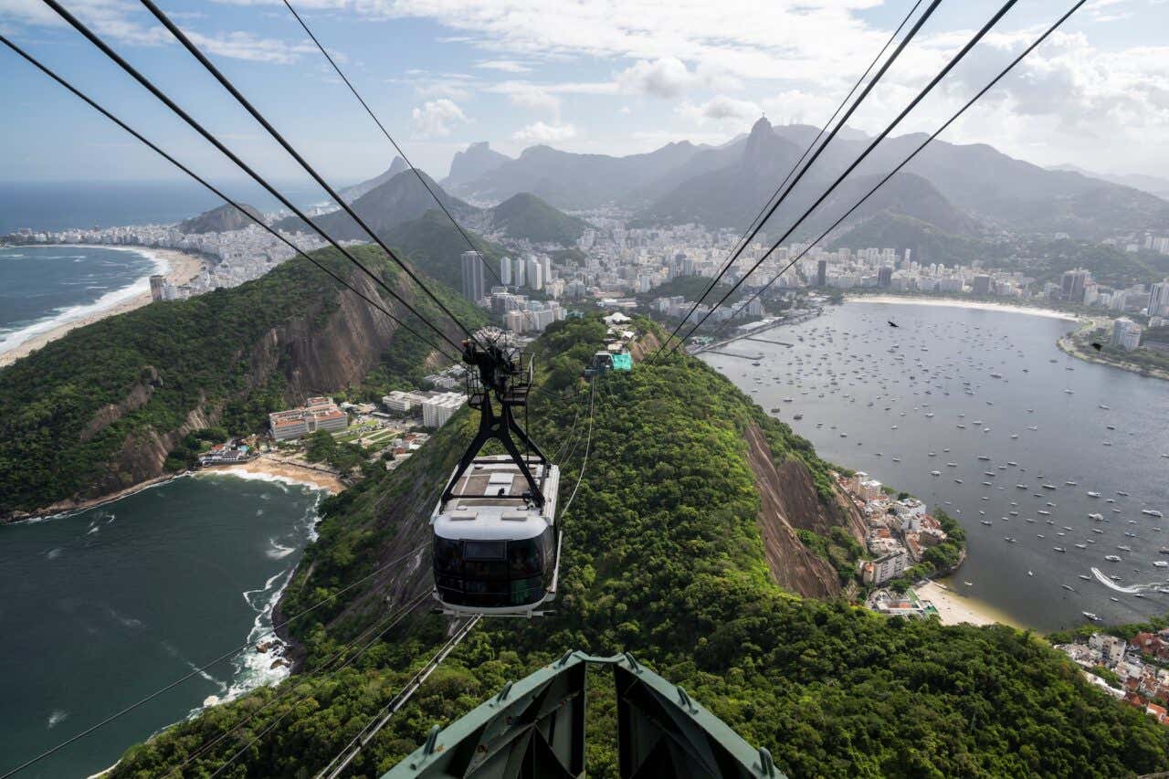 Panorâmica do bondinho descendo os cabos com a cidade do Rio de Janeiro ao fundo