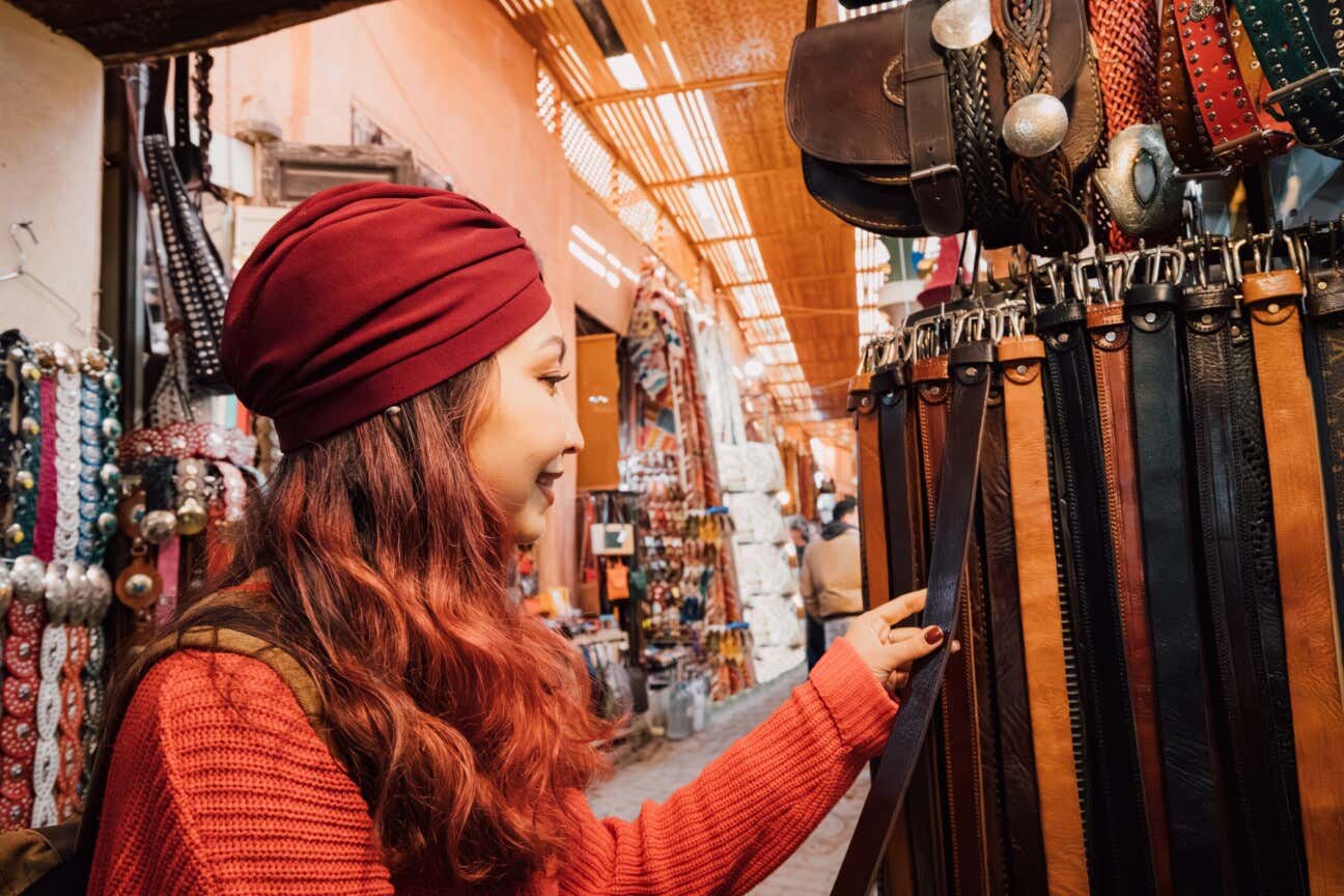 Una giovane donna osserva delle cinture in cuoio artigianali in una bancarella del mercato di Marrakech