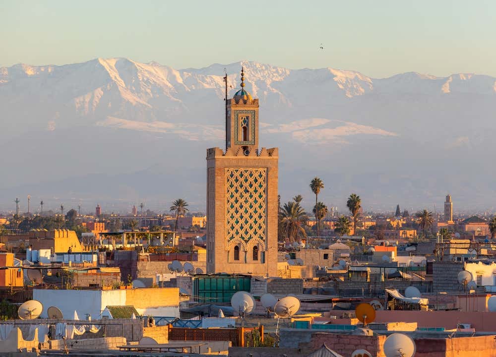 Vista panoramica su un minareto di Marrakech con sullo sfondo le montagne innevate marocchine