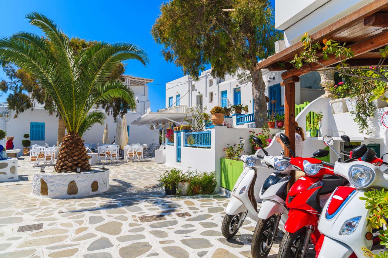 Scooter garés sur une petite place aux maisons blanc et bleu de Santorin