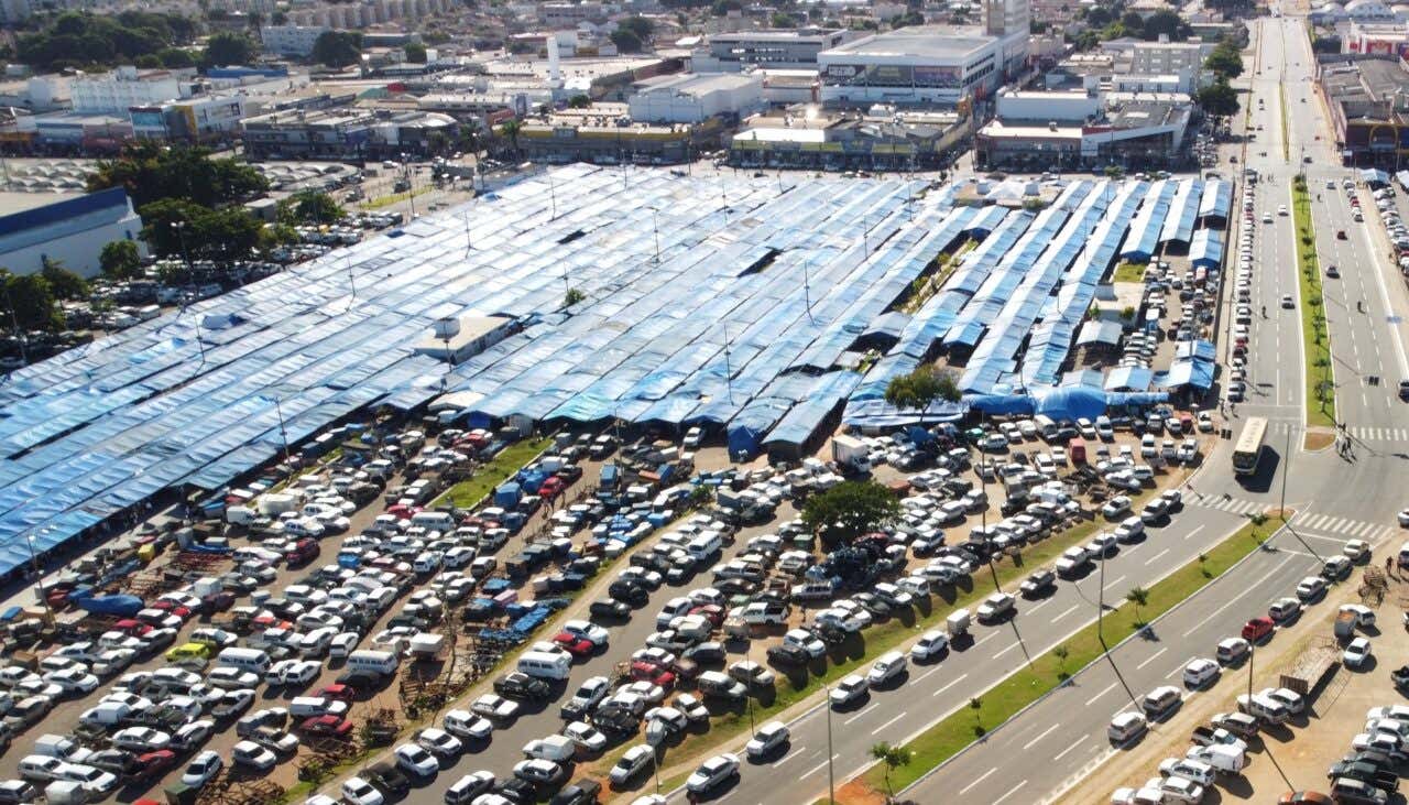 Vista aérea da Feira Hippie com barracas e um estacionamento lotado de veículos