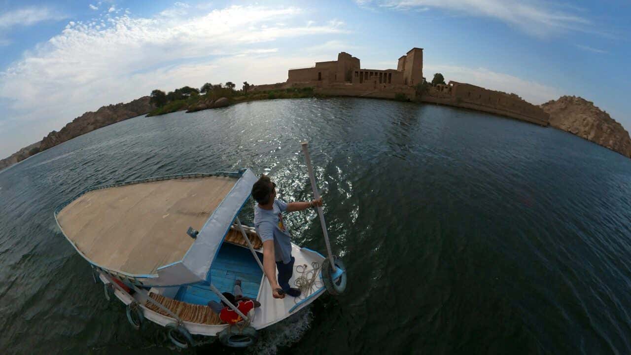 Un hombre en una embarcación con el Templo de Filae en el fondo.