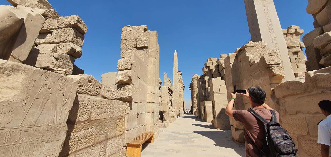 Un hombre tomando una fotografía de las columnas del Templo de Karnak en Egipto.