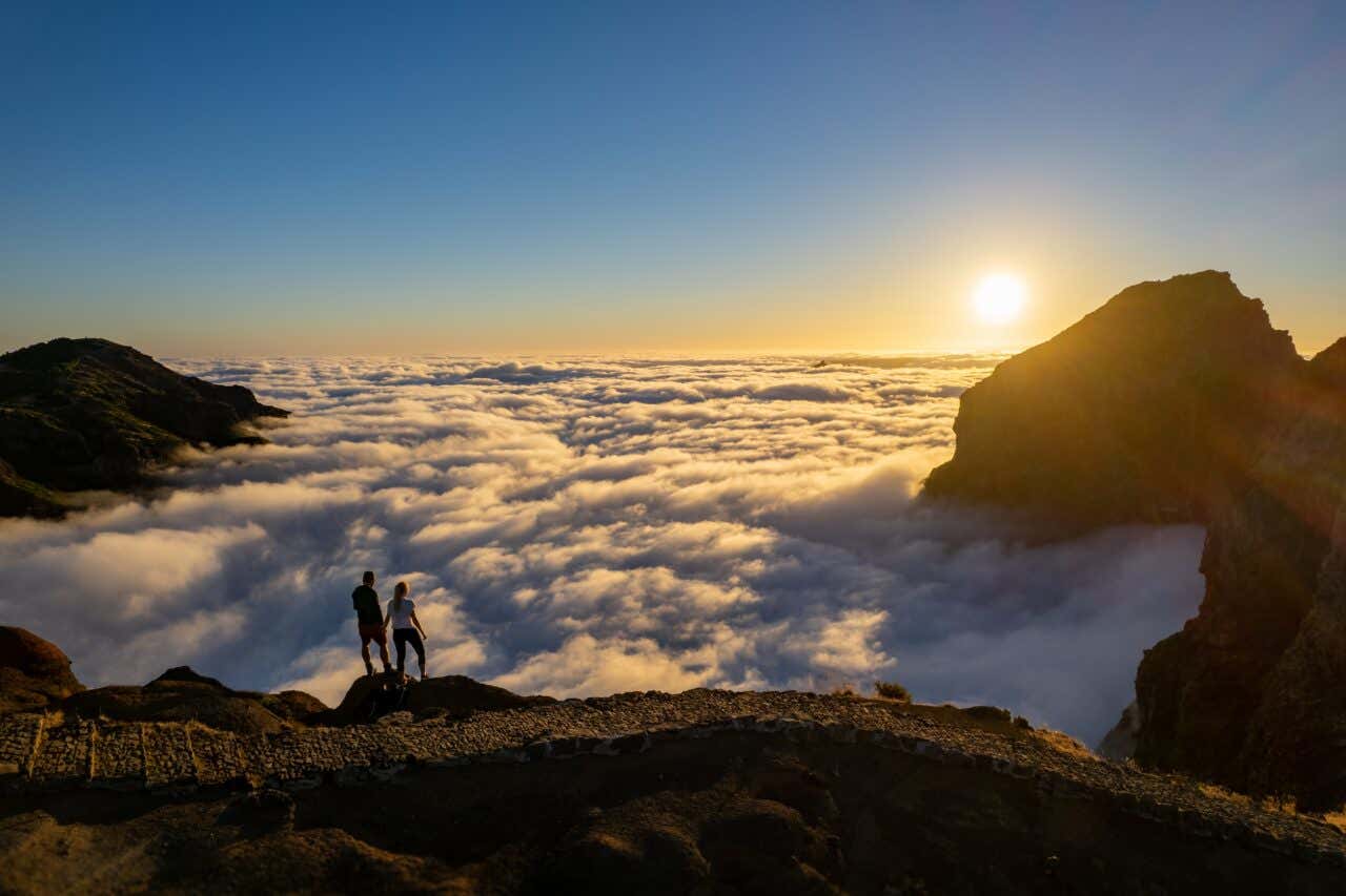 Deux personnes face au lever de soleil et une mer de nuages au Pico do Arieiro
