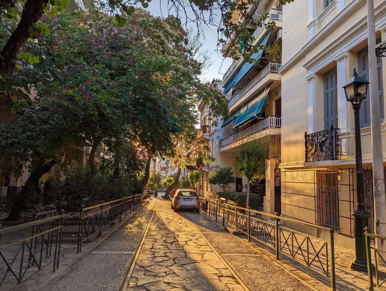 A dimly lit street in Athens with trees along the street.