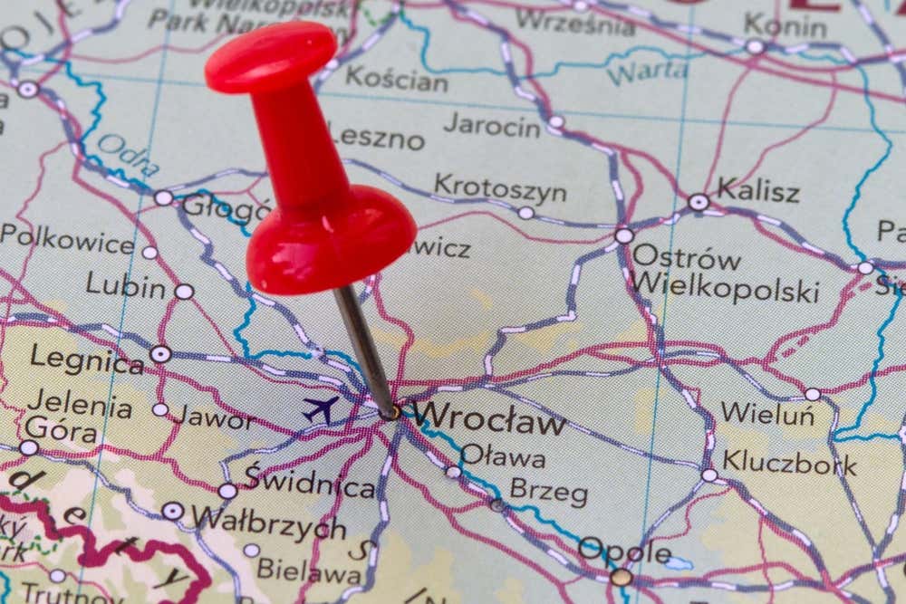 Primo piano di una mappa geografica della Polonia con una puntina da disegno rossa fissata esattamente sulla città di Breslavia (Wrocław), circondata da altre località come Legnica, Kalisz e Opole