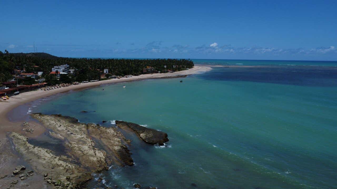 Uma paradisíaca enseada tropical com águas turquesa e falésias cobertas de coqueiros