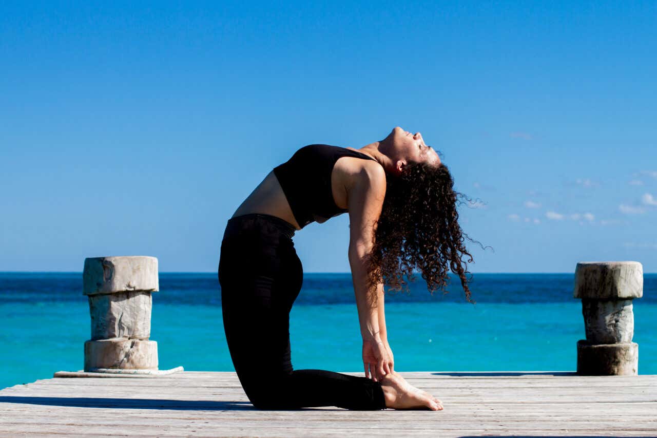 Femme faisant du yoga face à la mer à Tulum