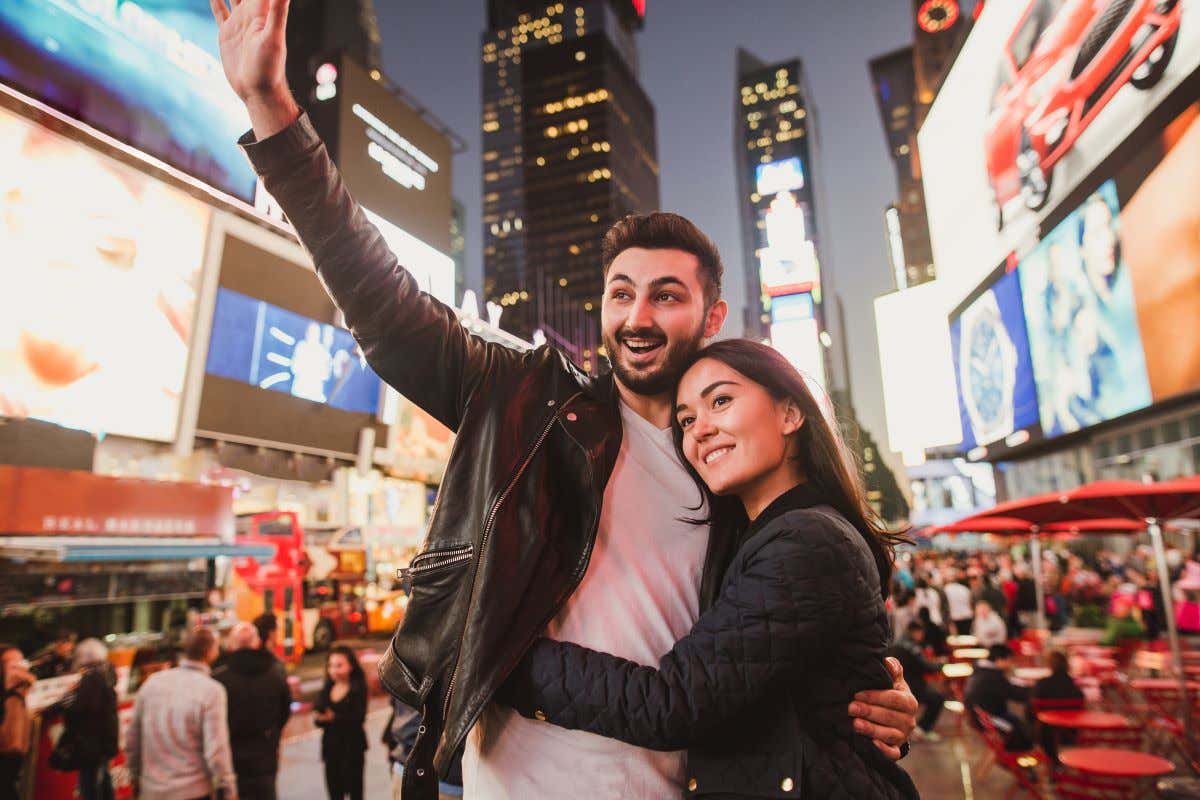 Pareja en Times Square, Nueva York, capturando un momento especial con una selfie