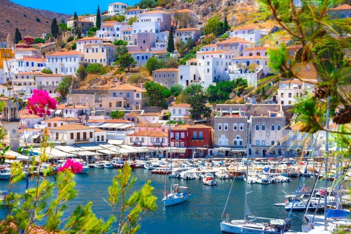 Views of the port of Hydra in Greece with many sailboats and houses on a sunny day.