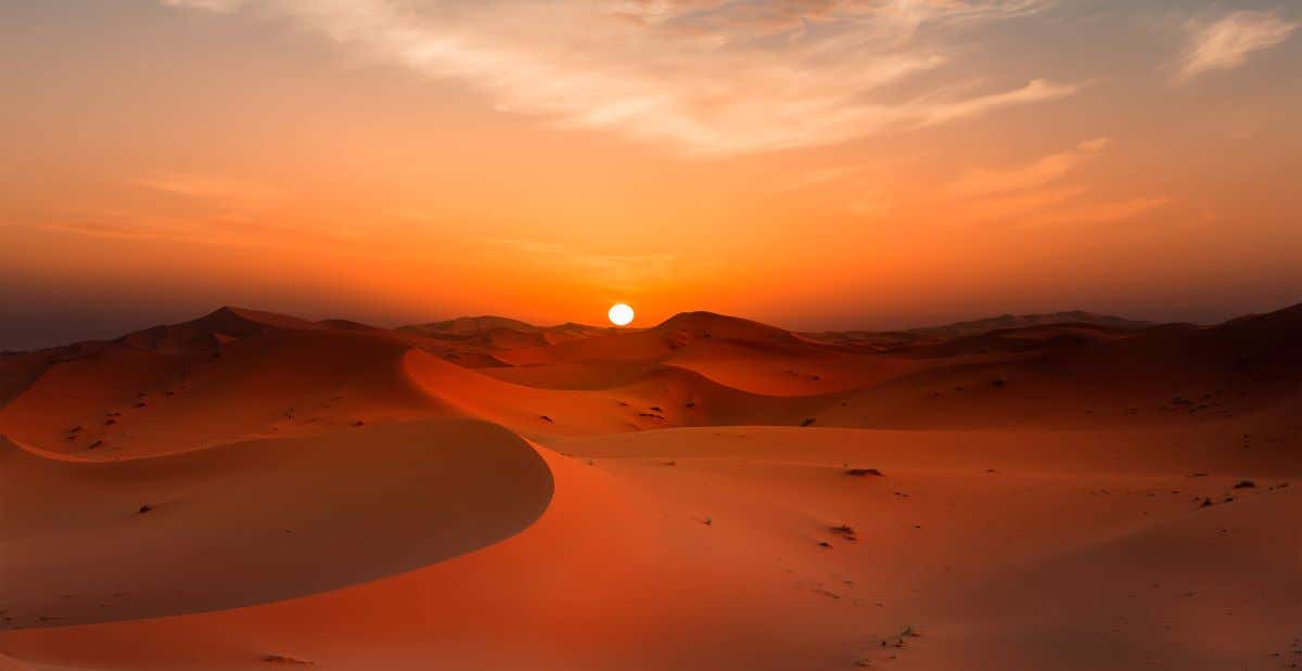 Vista panorámica del desierto de Merzouga con las dunas y el atardecer de fondo