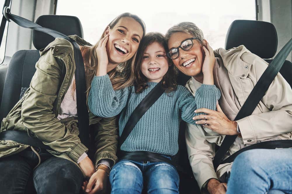 A family of two women and a young girl sitting in a car