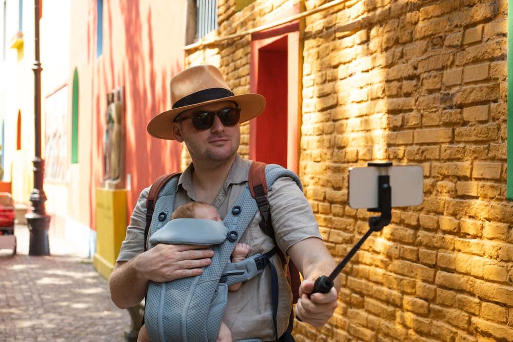 A man wearing a baby carrier taking a selfie in Buenos Aires