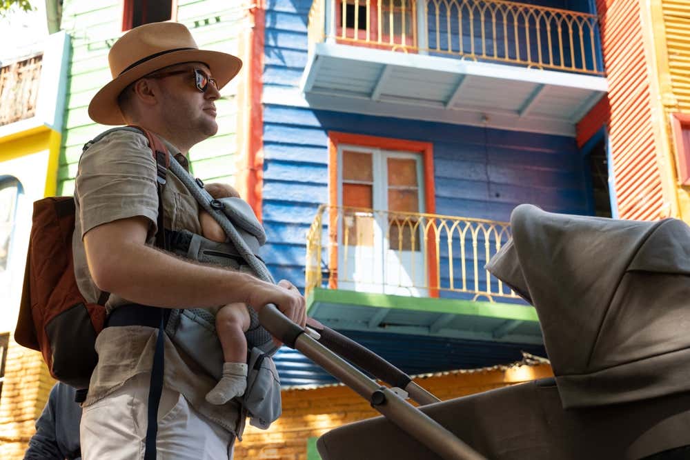 A father pushing a stroller through the streets of La Boca, Buenos Aires