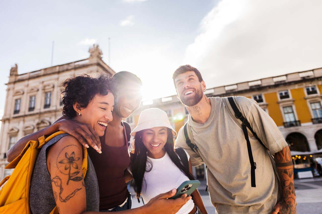Group of friends looking at a phone in Praça do Comércio in Lisbon