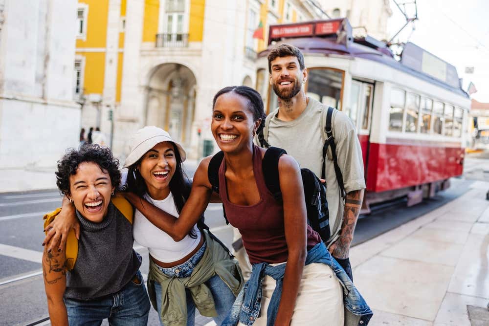 Friends posing in front of a red tram in Lisbon