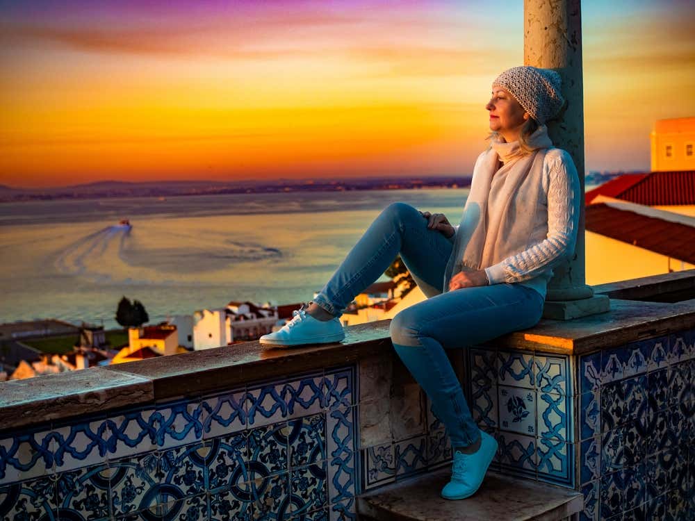 Woman sitting on the balcony of the Santa Luzia viewpoint in Lisbon watching the evening light
