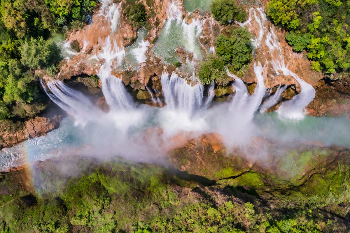 Vista aérea de la caída de agua de la cascada de Tamul, formando un arcoíris entre la vegetación