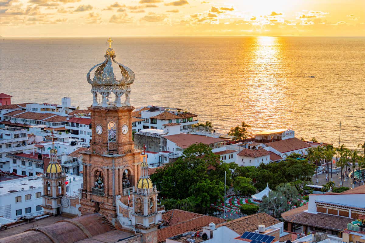 Iglesia de Nuestra Señora de Guadalupe, un templo que destaca por su alta torre del reloj y dos pequeñas cúpulas doradas que brillan al atardecer junto al mar