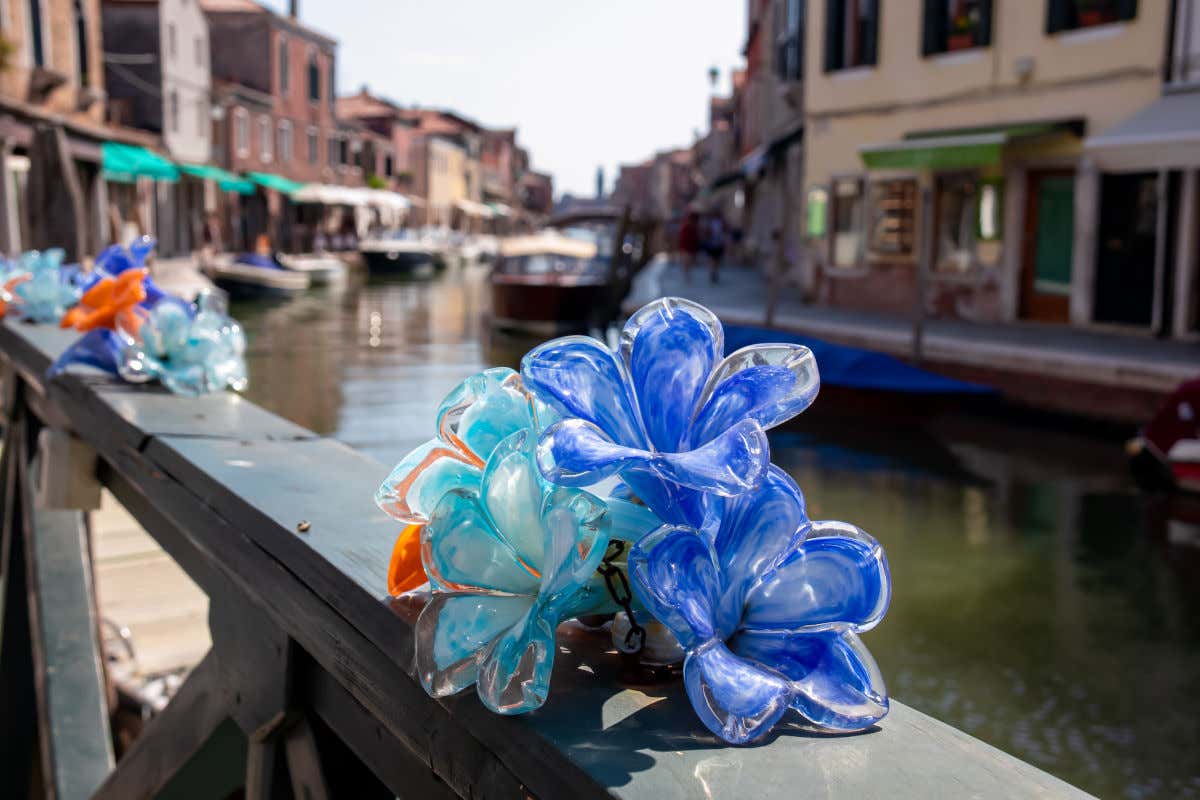 Flores hechas con cristal de Murano en una barandilla de un puente con vistas a un canal de la isla