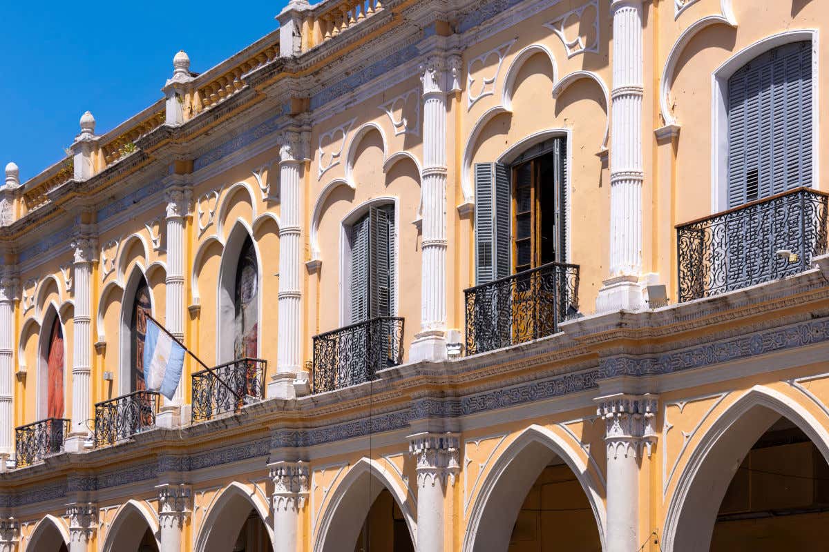 Fachada del Museo de Arqueología de Alta Montaña, con colores amarillso y blancos y varios arcos en sus dos pisos de altura