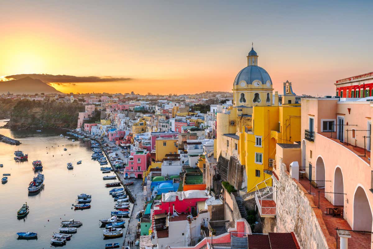 Casas de colores iluminadas con los colores del atardecer en la isla de Procida y junto a un pequeño puerto pesquero
