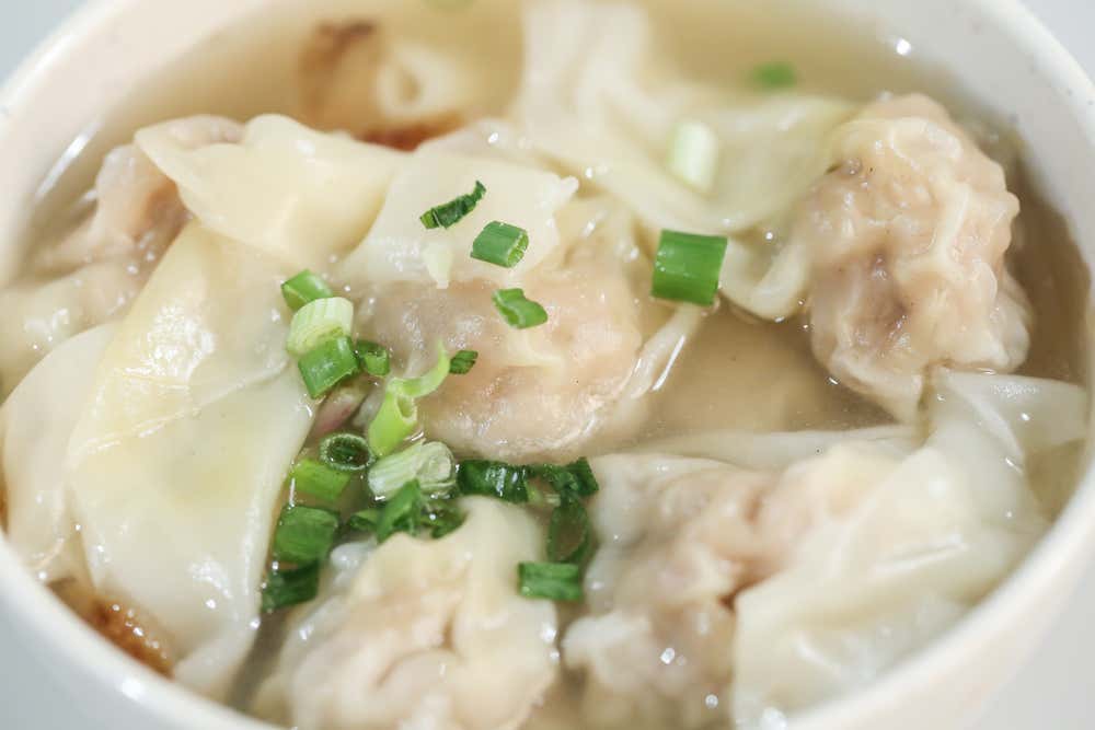 Detalhe de uma tigela de sopa de wonton, preparada com caldo quente e bolinhos recheados, um prato tradicional da culinária chinesa