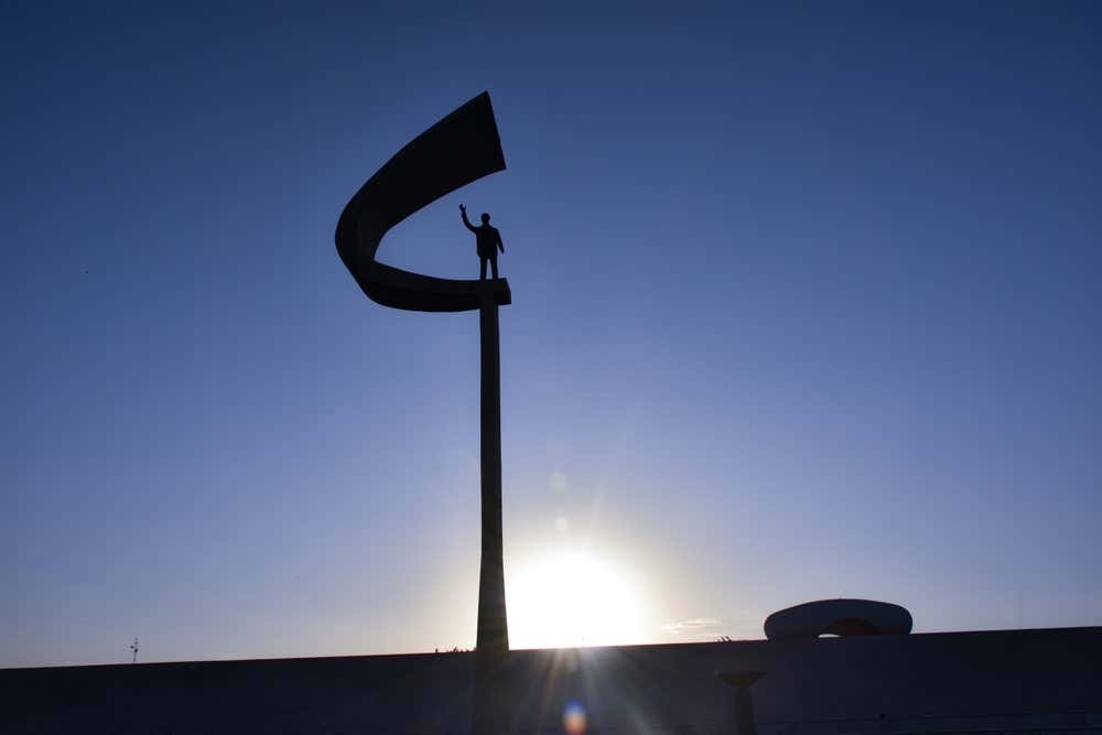 Detalhe do Memorial JK, em Brasília, com foco seletivo destacando sua arquitetura modernista e a escultura de Juscelino Kubitschek, enquanto o fundo permanece desfocado