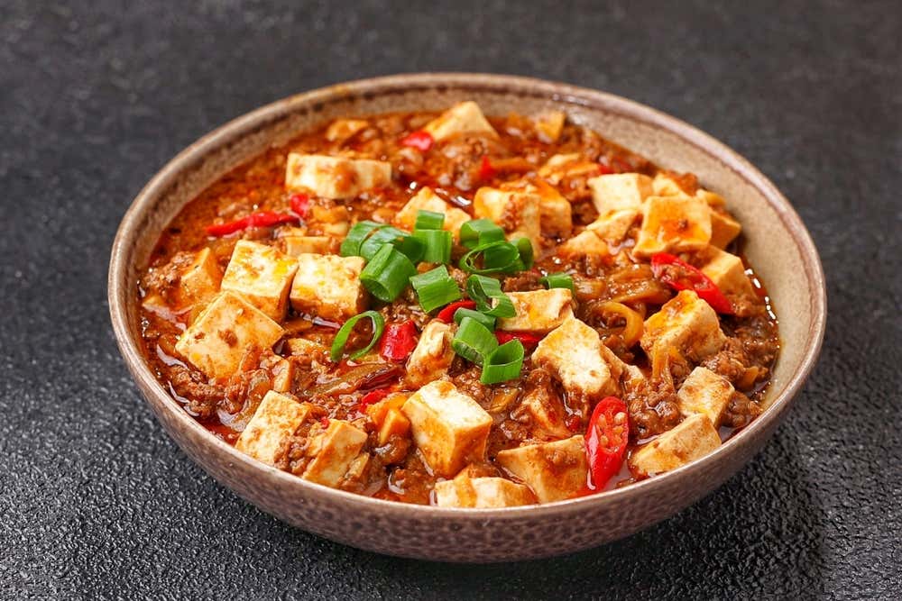 Detalhe de um prato de Mapo tofu, prato tradicional da província de Sichuan, preparado com tofu macio, carne moída e temperos típicos, como doubanjiang e pimenta-de-Sichuan