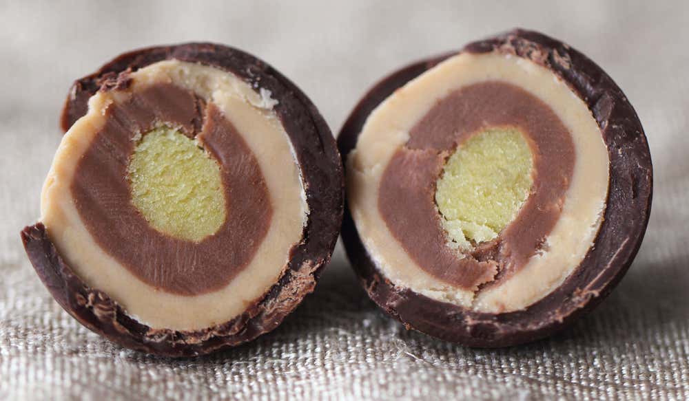 Due metà di una Palla di Mozart, che mostrano chiaramente gli strati interni: guscio di cioccolato fondente, torrone, crema al cioccolato e cuore di marzapane al pistacchio verde