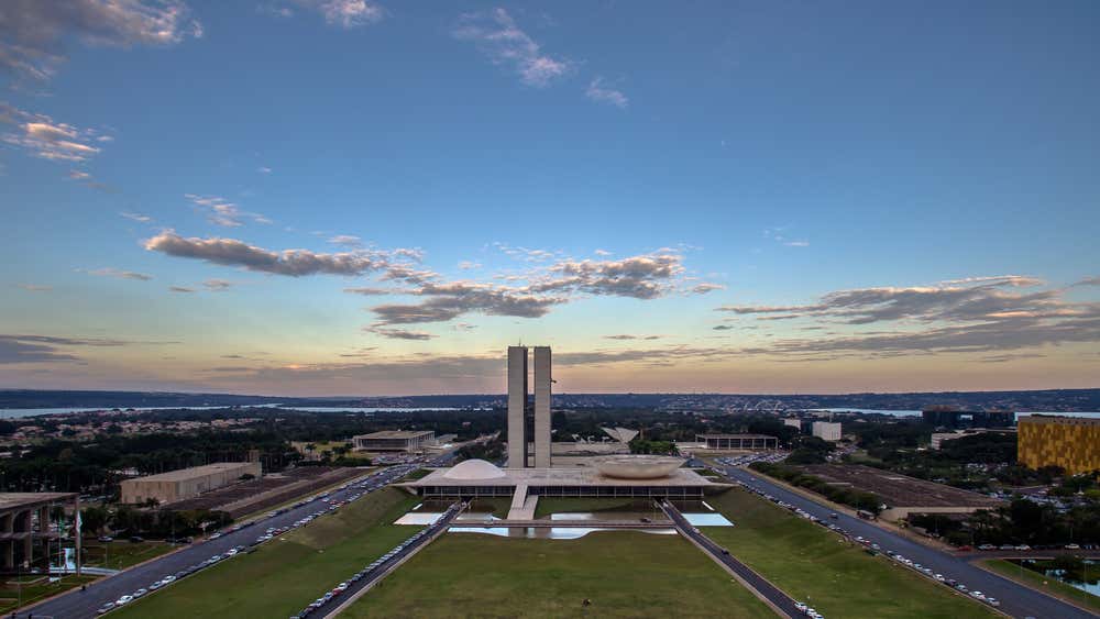 Pôr do sol sobre o Congresso Nacional, em Brasília, Distrito Federal, Brasil, com o céu iluminado pelos tons dourados do entardecer refletindo na arquitetura modernista do complexo
