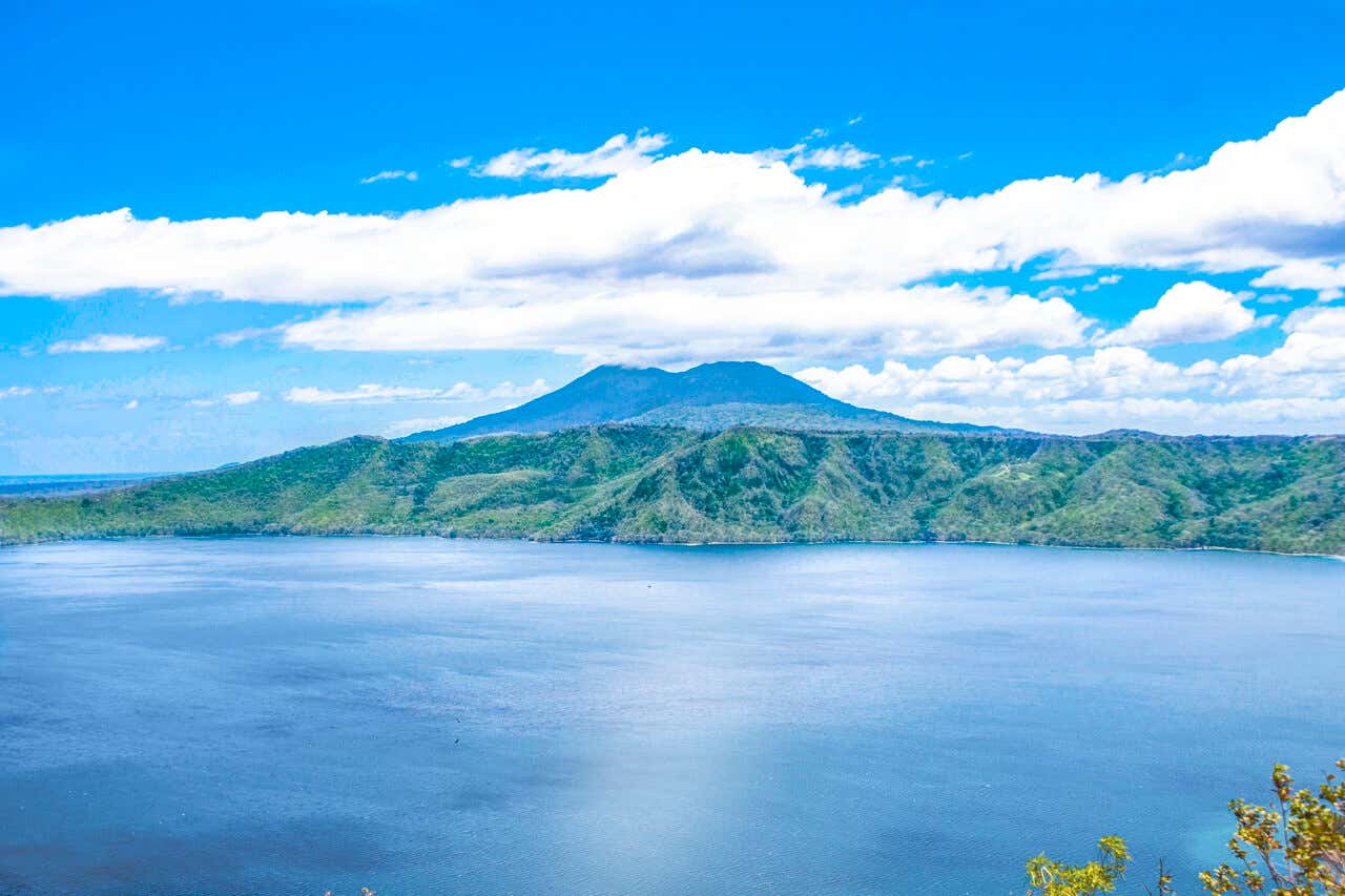 Vista panorámica de la Laguna de Apoyo rodeada de colinas verdes bajo un cielo azul