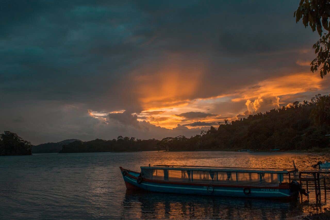 Embarcación amarrada a la orilla del Río San Juan durante un atardecer con cielo anaranjado