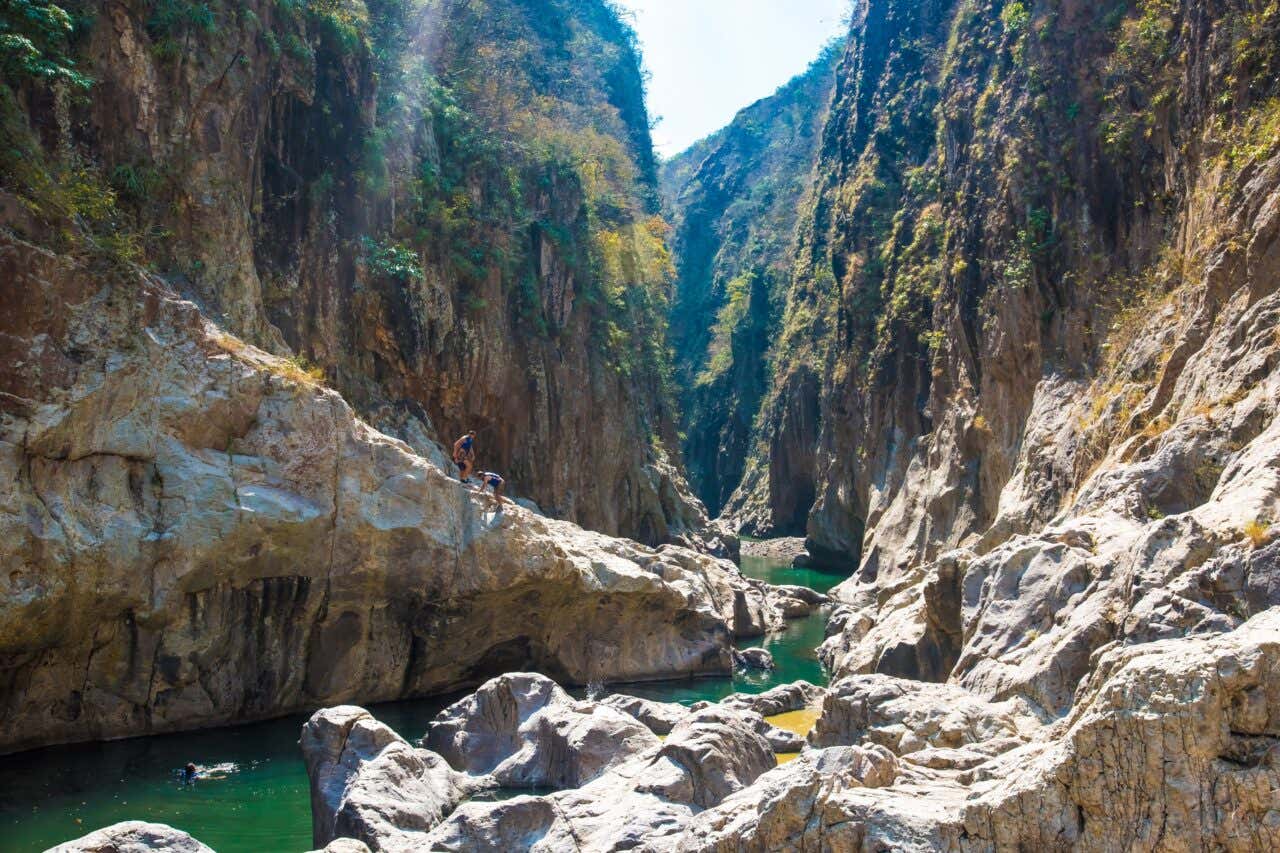 Personas explorando las paredes rocosas y el río en el Cañón de Somoto