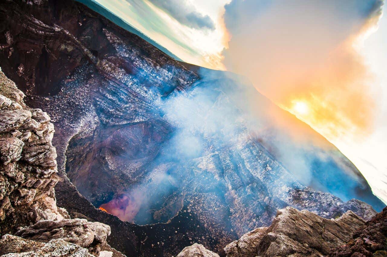 Vista del cráter del volcán Masaya emanando columna de gases y humo al atardecer