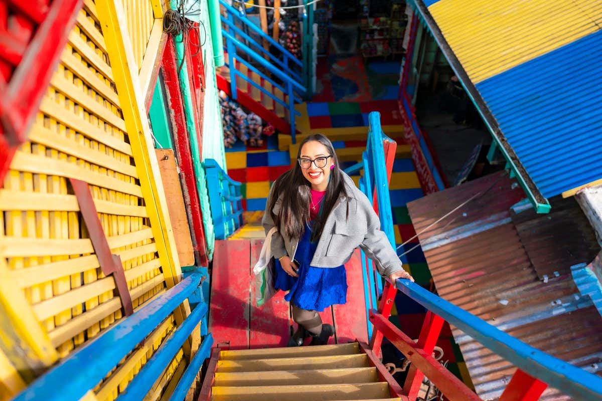 Turista subiendo una escalera de colores vivos en el barrio de La Boca en Buenos Aires