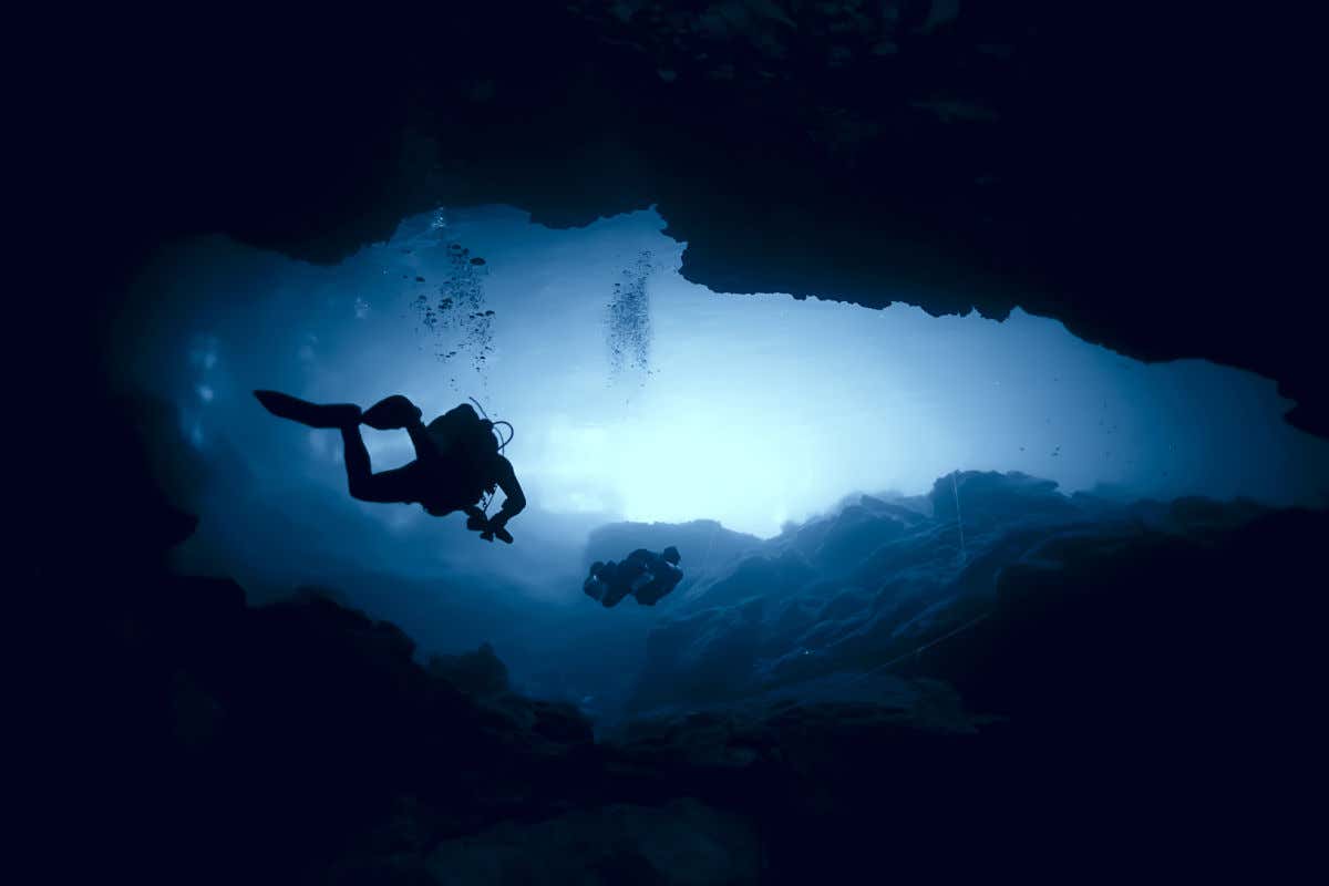 Dos personas haciendo submarinismo o buceo en el interior de un cenote